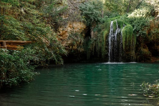 Long exposure waterfall during the day. green forest and rocky mountain. summer time. crystal clear blue water. beautiful waterfall with blue lake in the forest