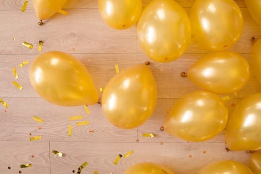 golden balloons and confetti on a wooden floor. preparation for a birthday or other party.