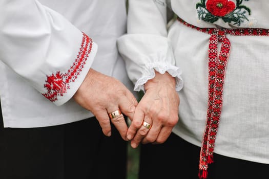 Close up of senior man and woman holding hands and walking outdoors. Rear view of old couple walking hand in hand outdoors. the old couple is holding hands