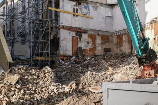 Ruined house. An excavator destroys a house with a bucket.
