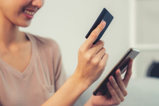 Contented young woman eagerly makes an online purchase using her smartphone. E-commerce business, online purchasing.