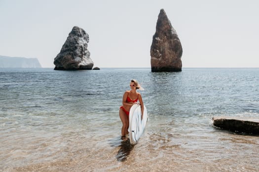 Close up shot of beautiful young caucasian woman with black hair and freckles looking at camera and smiling. Cute woman portrait in a pink bikini posing on a volcanic rock high above the sea