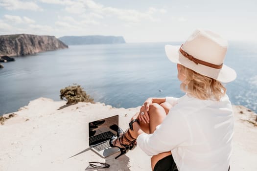 Happy girl doing yoga with laptop working at the beach. beautiful and calm business woman sitting with a laptop in a summer cafe in the lotus position meditating and relaxing. freelance girl remote work beach paradise