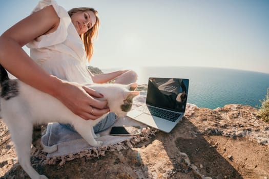 Woman sea laptop. Business woman in yellow hat working on laptop by sea. Close up on hands of pretty lady typing on computer outdoors summer day. Freelance, digital nomad, travel and holidays concept.