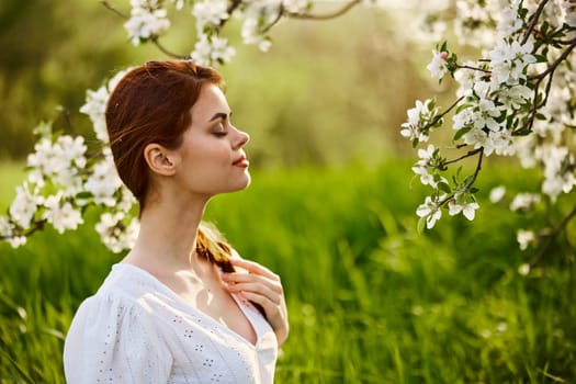 portrait of a beautiful woman looking at the flowers of an apple tree. High quality photo