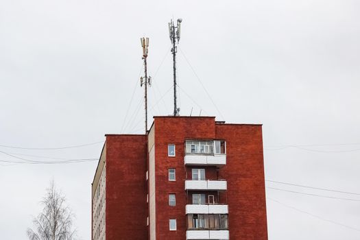 Antenna on a tall apartment building on white sky background
