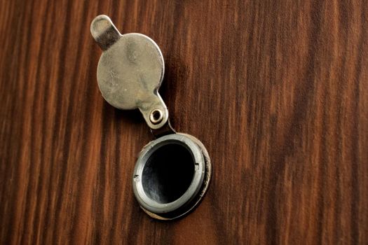 Peephole at the door with a wooden texture close up