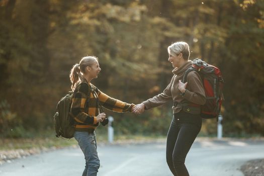 Shot of a teen girl and her mom having fun during walk together through the forest in autumn.