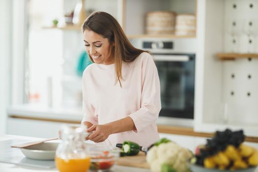 Shot of a young woman preparing a healthy meal on the stove in her kitchen.