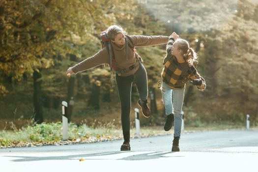 Shot of a teen girl and her mom walking together through the forest in autumn.