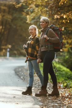 Shot of a teen girl and her mom walking together through the forest in autumn.