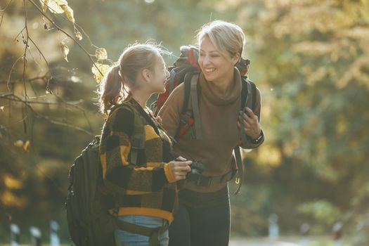 Shot of a teen girl and her mom walking together through the forest in autumn.