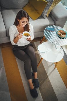 Shot of an attractive young woman drinking tea at her home.