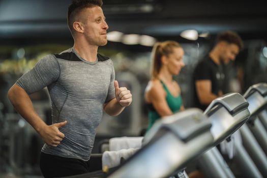 Shot of a young man running on a treadmill at the gym.