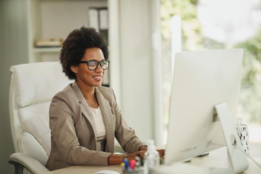 Shot of an African businesswoman sitting alone in her home office and working on computer during COVID-19 pandemic.