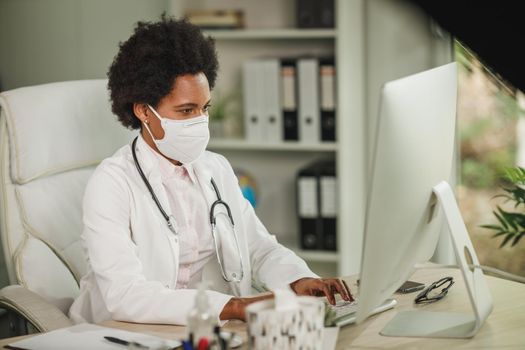 Shot of an African female doctor sitting alone in her office and working on computer during COVID-19 pandemic.