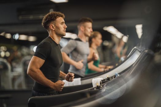 Shot of a young man jogging on a treadmill at the gym.