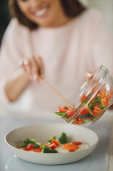 Cropped shot of a young woman preparing a healthy meal on the stove in her kitchen.