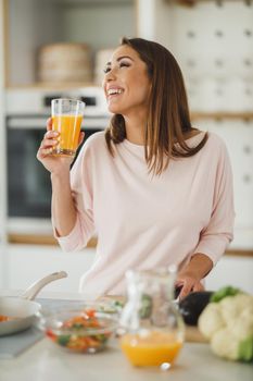 Shot of a young woman drinking fresh orange juice in her kitchen.