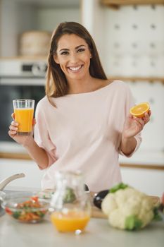 Shot of a young woman drinking fresh orange juice in her kitchen.