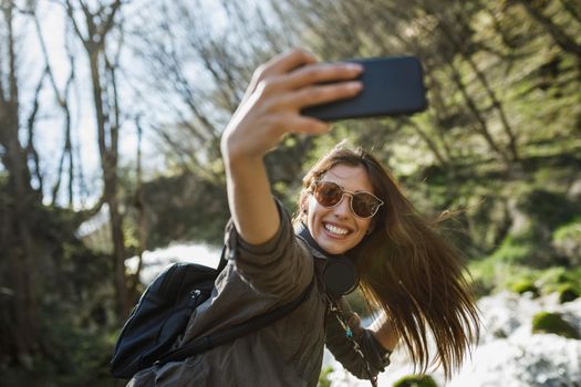 A carefree young woman making selfie with her smartphone while enjoying the outdoors.