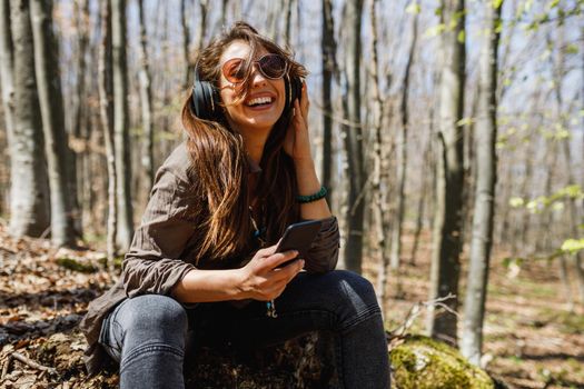 Shot of a cheerful young woman listening music  while enjoying the outdoors.