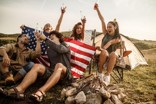 A group of cheerful friends having fun outside their tent at a festival.