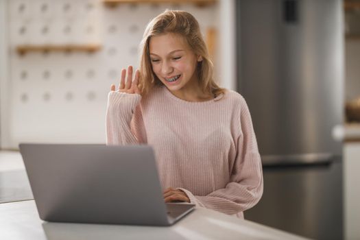 Shot of a cute teenage girl making a video call on laptop while having leisure time at her home during corona virus pandemic.