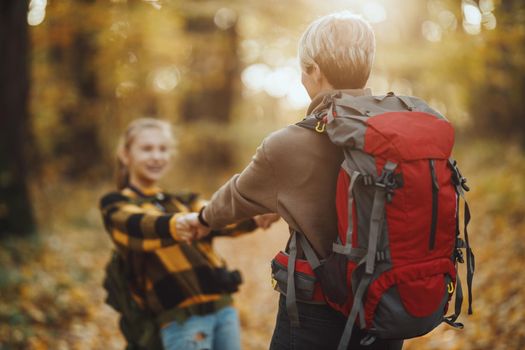 Shot of a teen girl and her mom having fund during walk together through the forest in autumn.