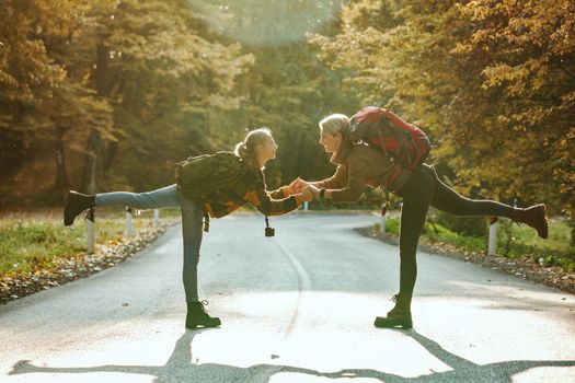 Shot of a cheerful teen girl and her mom having fun and playing during walk together through the forest in autumn.