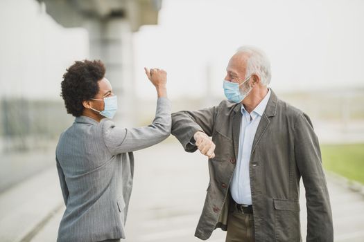 Shot of a multi-ethnic business people greeting with bumping elbows outdoors during corona virus pandemic to avoid handshakes.