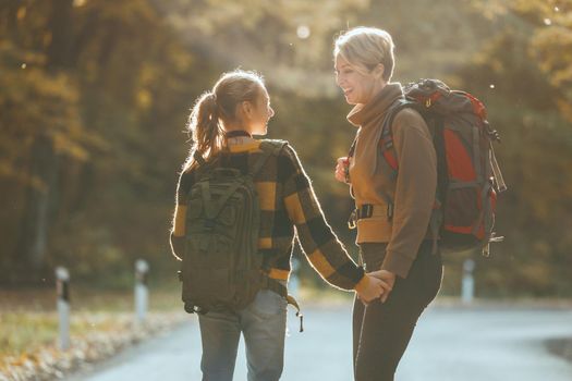 Shot of a teen girl and her mom talking during walk together through the forest in autumn.