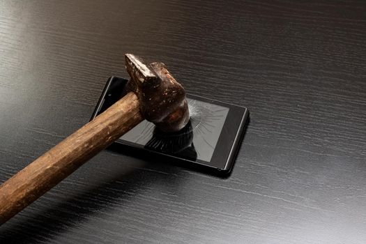 Phone under hammer close up on wooden table