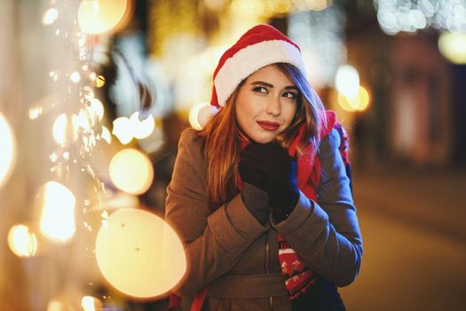 Shoot of a young woman is waiting for somebody in the city street at Christmas time.