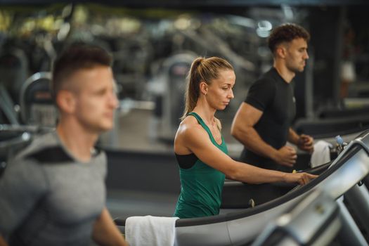 Shot of three young people exercising on a treadmill at the gym.