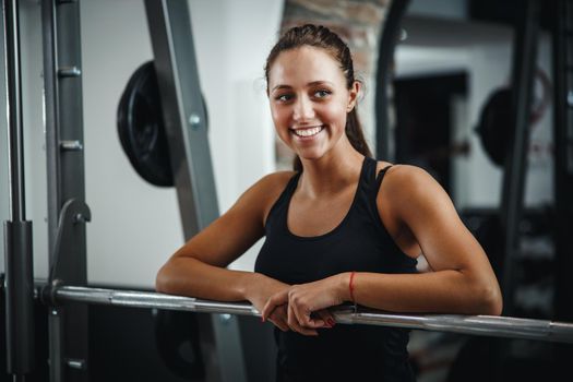 Shot of a muscular young woman in sportswear posing during getting ready to working out at the gym. She is preparing barbell before the start next series of exercises.