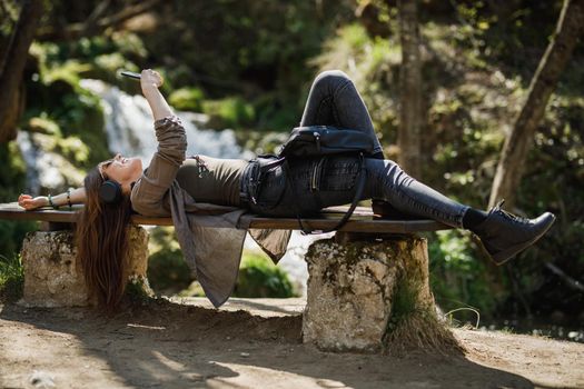 Shot of a carefree young woman listening music on her smartphone while enjoying the outdoors.