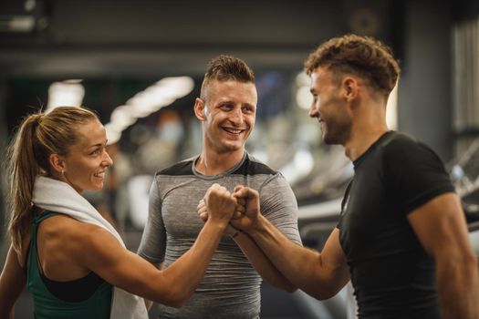 Shot of three young people joining their fists together in solidarity at a gym.