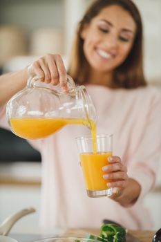 Cropped shot of a young woman drinking fresh orange juice in her kitchen.