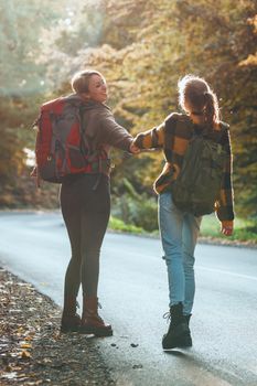 Shot of a teen girl and her mom having fun during walk together through the forest in autumn.