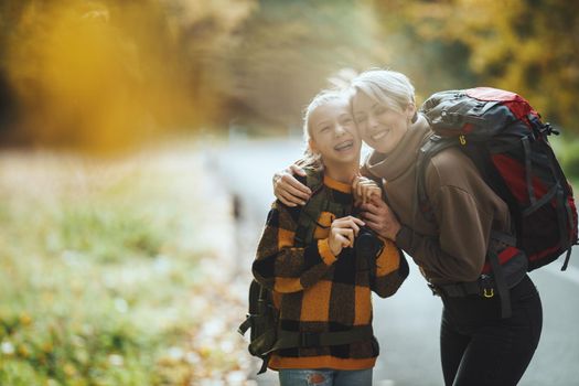 Shot of a teen girl and her mom having fun during walk together through the forest in autumn.