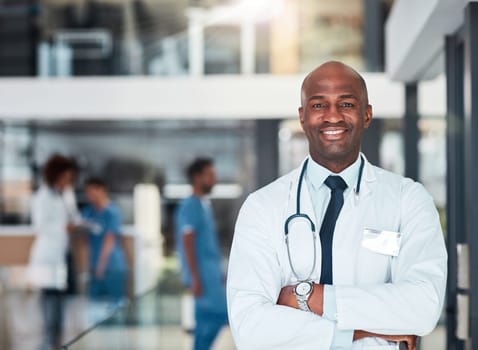 He has all the answers. Portrait of a cheerful young doctor standing with his arms folded inside of a hospital during the day