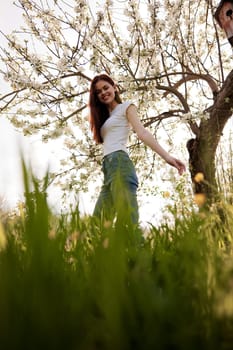 cute woman in light clothes posing next to a flowering tree in the countryside. High quality photo