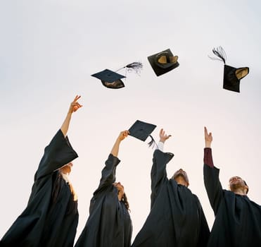 Celebrating the end of their academic years. a group of students throwing their hats in the air on graduation day