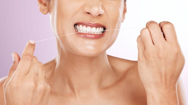 Face, woman and flossing teeth for cleaning, hygiene or tooth care in studio isolated on a purple background. Oral health, fresh breath or mature female model with dental floss or thread for wellness.