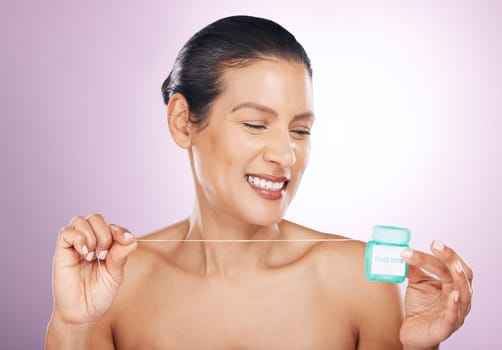 Face, smile and woman with dental floss for cleaning, hygiene or tooth care in studio isolated on a purple background. Oral health, cosmetics and happy mature female model flossing teeth for wellness.