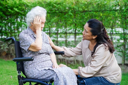 Caregiver help Asian elderly woman disability patient sitting on wheelchair in park, medical concept.