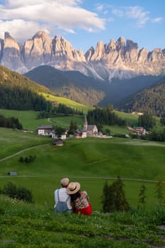 Couple viewing the landscape of Santa Maddalena Village in Dolomites Italy, Santa Magdalena village magical Dolomites mountains, Val di Funes valley, Trentino Alto Adige region, South Tyrol, Italy,