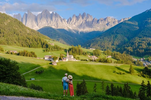 Couple viewing the landscape of Santa Maddalena Village in Dolomites Italy, Santa Magdalena village magical Dolomites mountains, Val di Funes valley, Trentino Alto Adige region, South Tyrol, Italy,