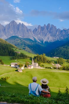 Couple viewing the landscape of Santa Maddalena Village Val di Funes, South Tyrol, Italy Dolomites, men and women visit Dolomites mountains, Val di Funes valley, Trentino Alto Adige, South Tyrol, Italy,